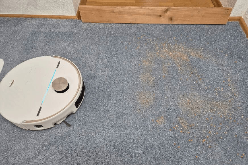 Dreame X60 vs MOVA V70 auf einem hellen Teppich mit feinem Sand beim Saugtest